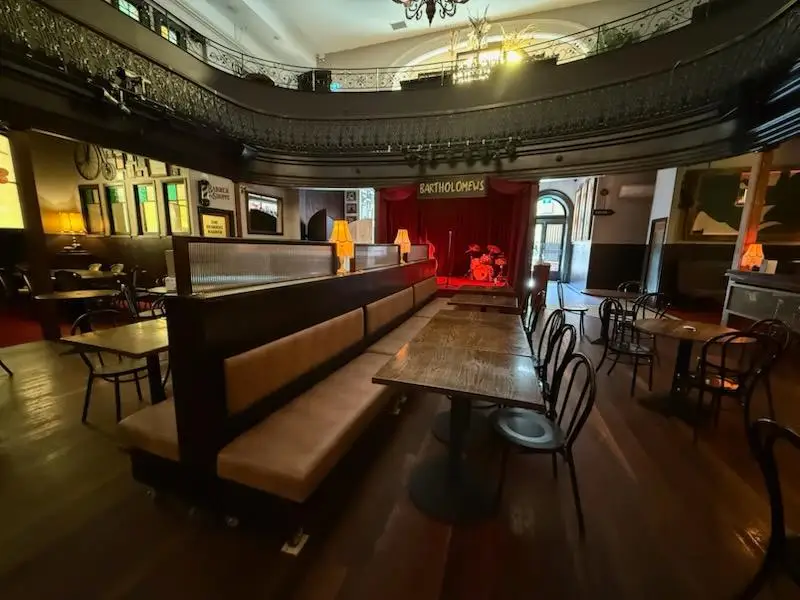 Double sided banquette spine seating with timber tables and bentwood chairs facing a stage