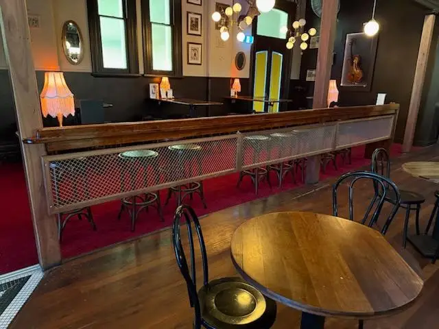 Timber drink rail with woven mesh infill and stools facing a raised dining area