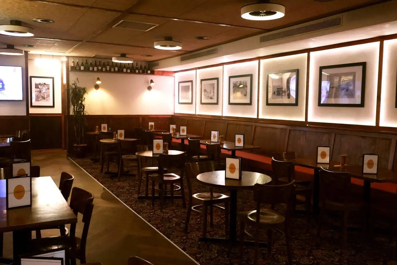 Pub bistro dining room with banquette seating, timber wainscoting and backlit framed artwork
