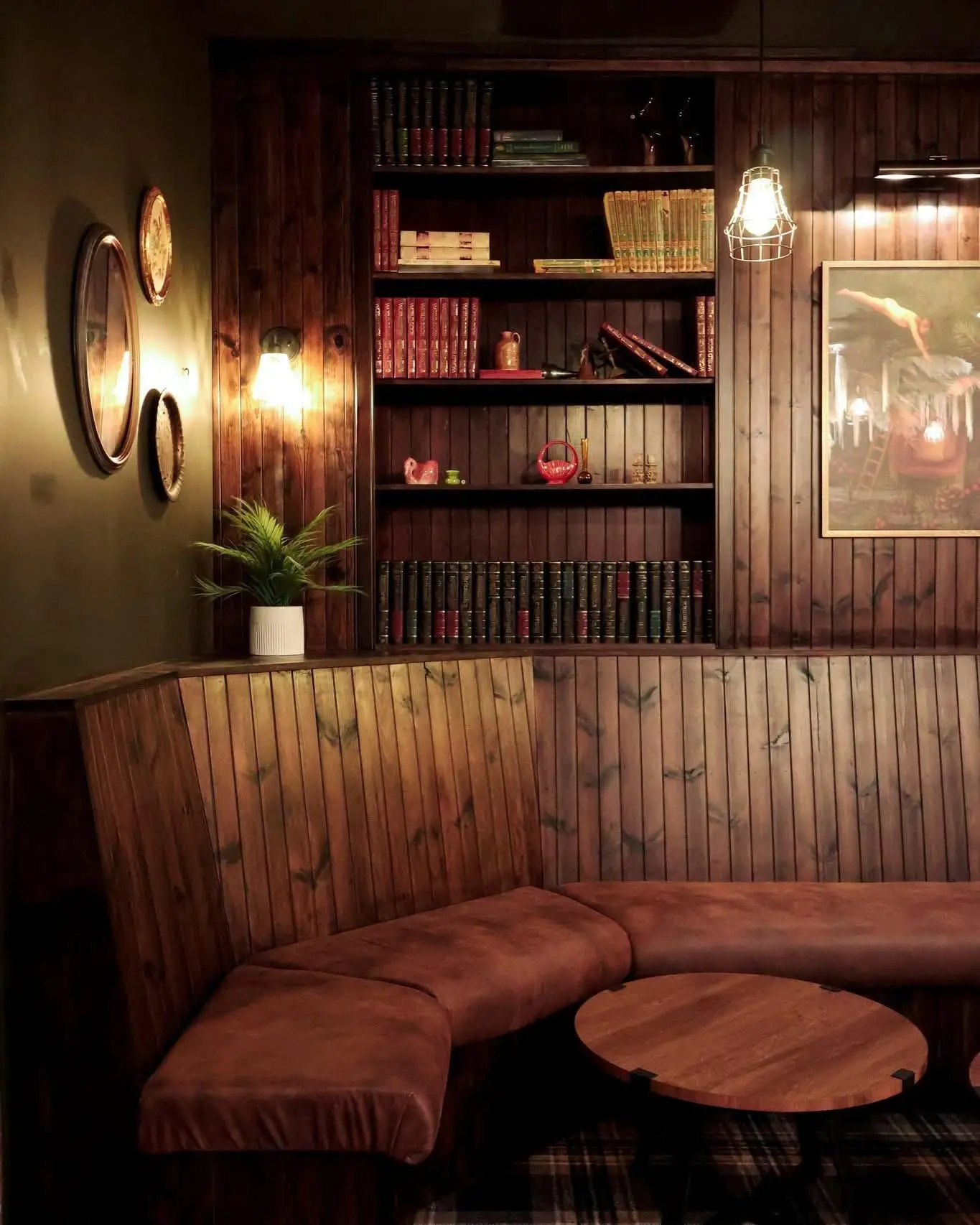 Corner booth with beadboard panelling, built in bookshelf joinery and a round timber table