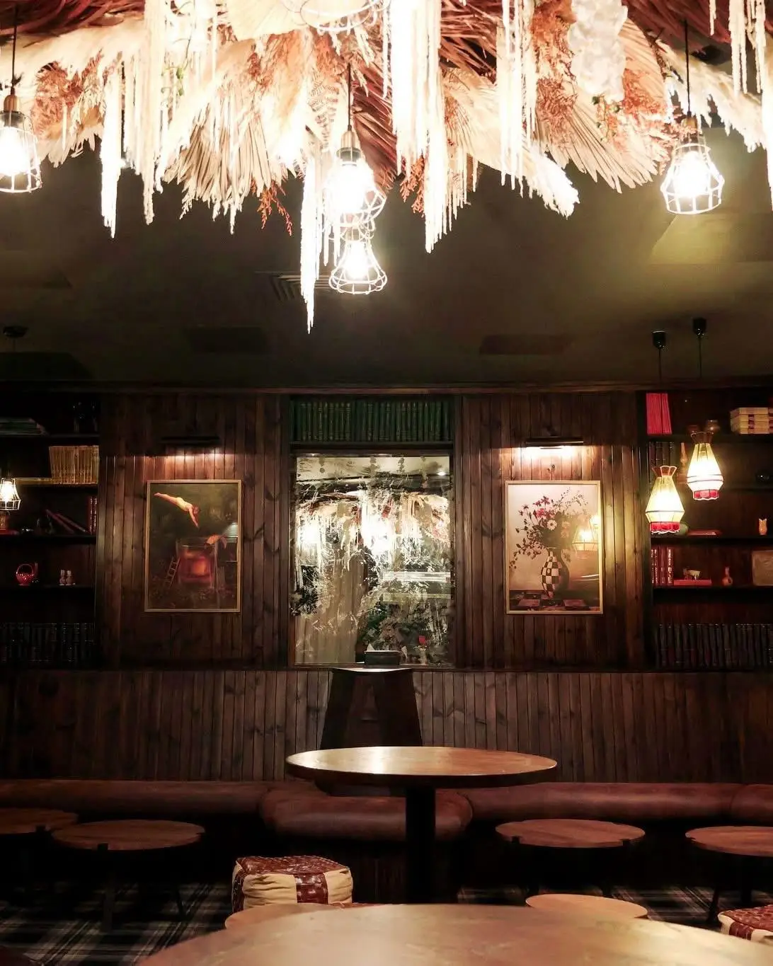 Cocktail bar with timber panelled walls, banquette seating and a dried floral ceiling feature