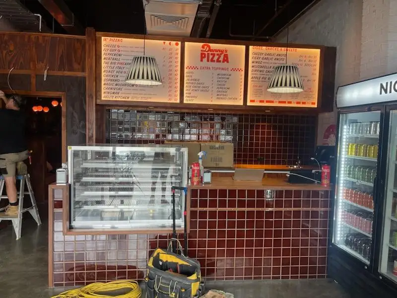 Pizza servery counter under construction with tiled front, timber bench and menu boards above