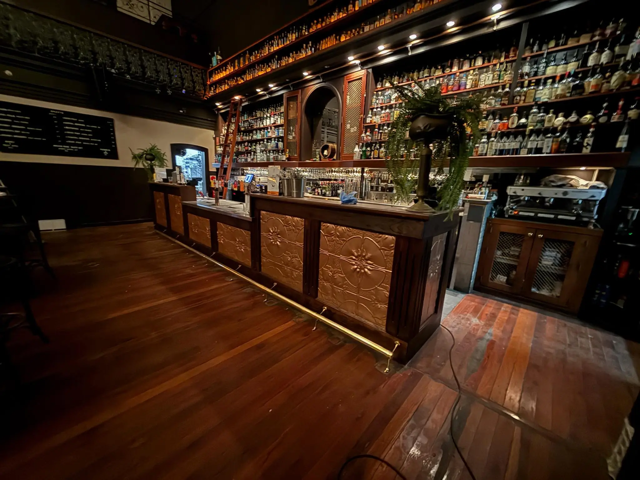 Public bar counter with pressed metal panelling and timber bar top running the length of the room