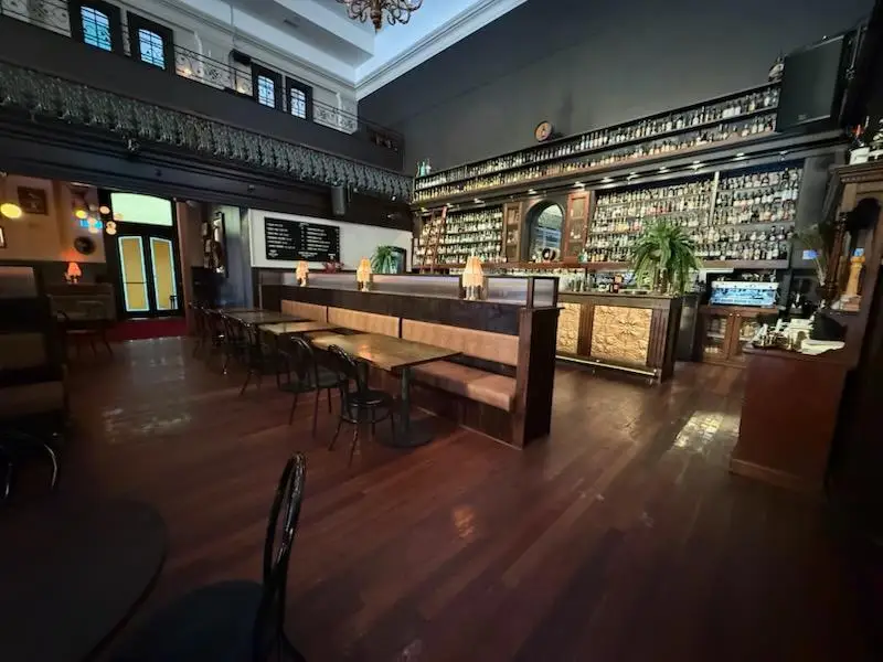 Pub lounge with banquette booth seating, timber tables and the back bar beyond