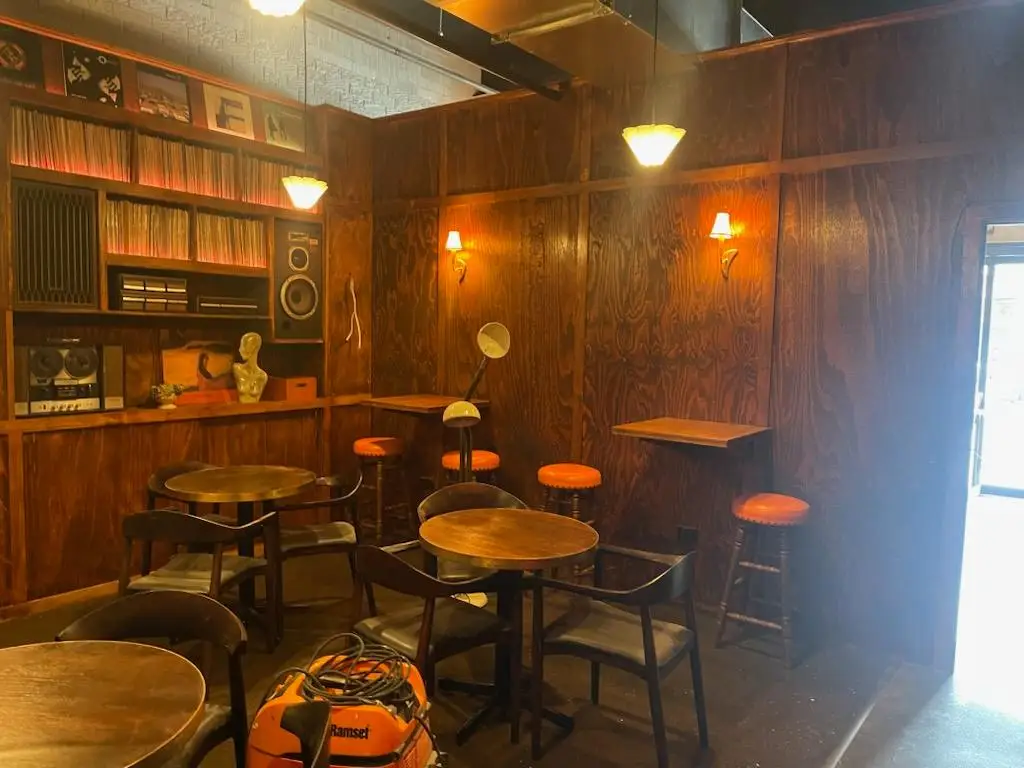 Timber lined lounge with record shelving joinery, wall lights and bar stools