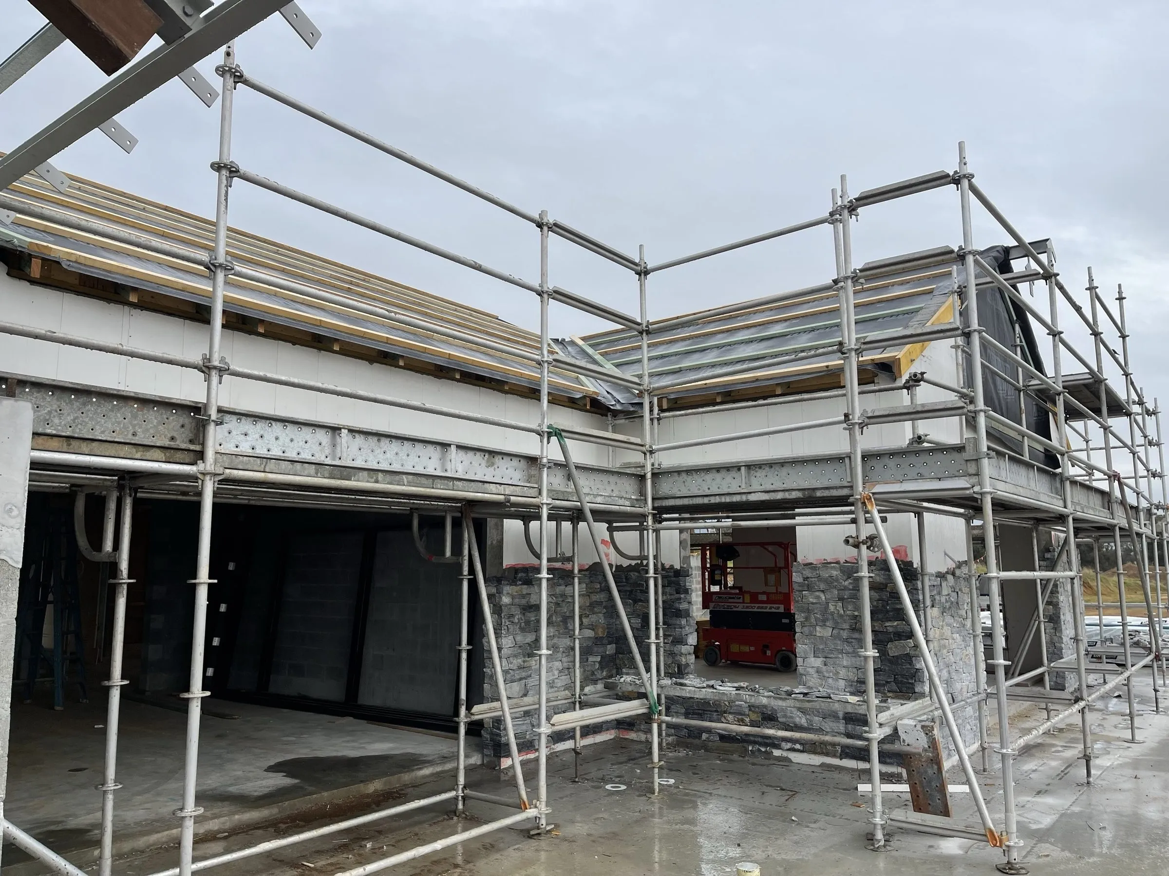 Two-storey home extension under construction in Newcastle with scaffolding and new brickwork