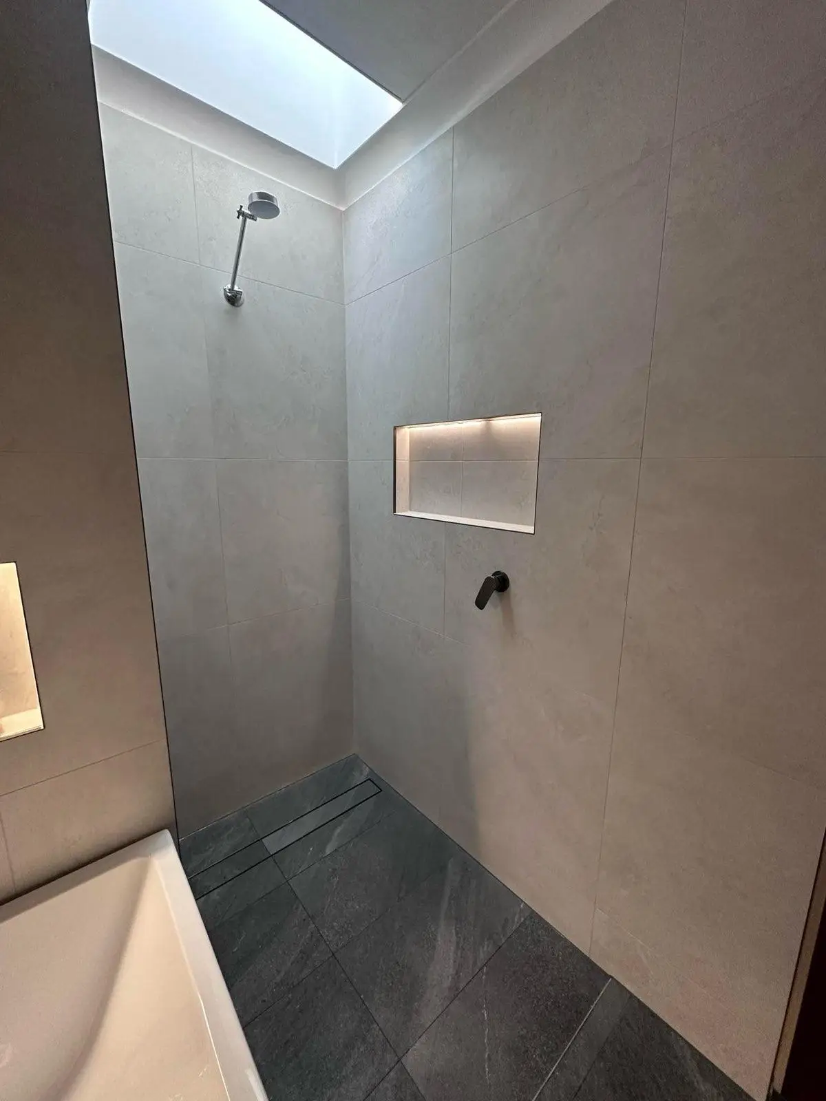 Walk-in shower with a skylight above in a renovated bathroom